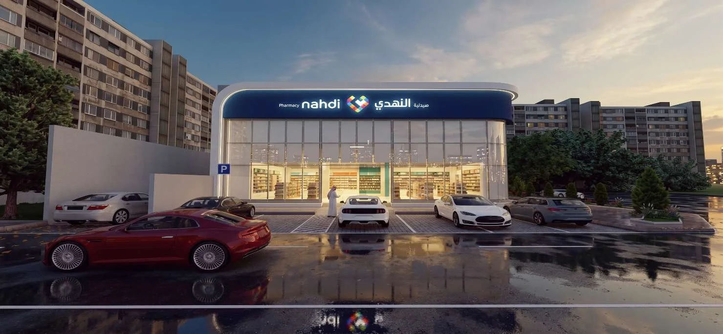 منظور تصميمي لواجهة الصيدلية عند الغسق: واجهة زجاجية منحنية بكامل الارتفاع أسفل لوحة صيدلية النهدي، والمواقف أمامها.
