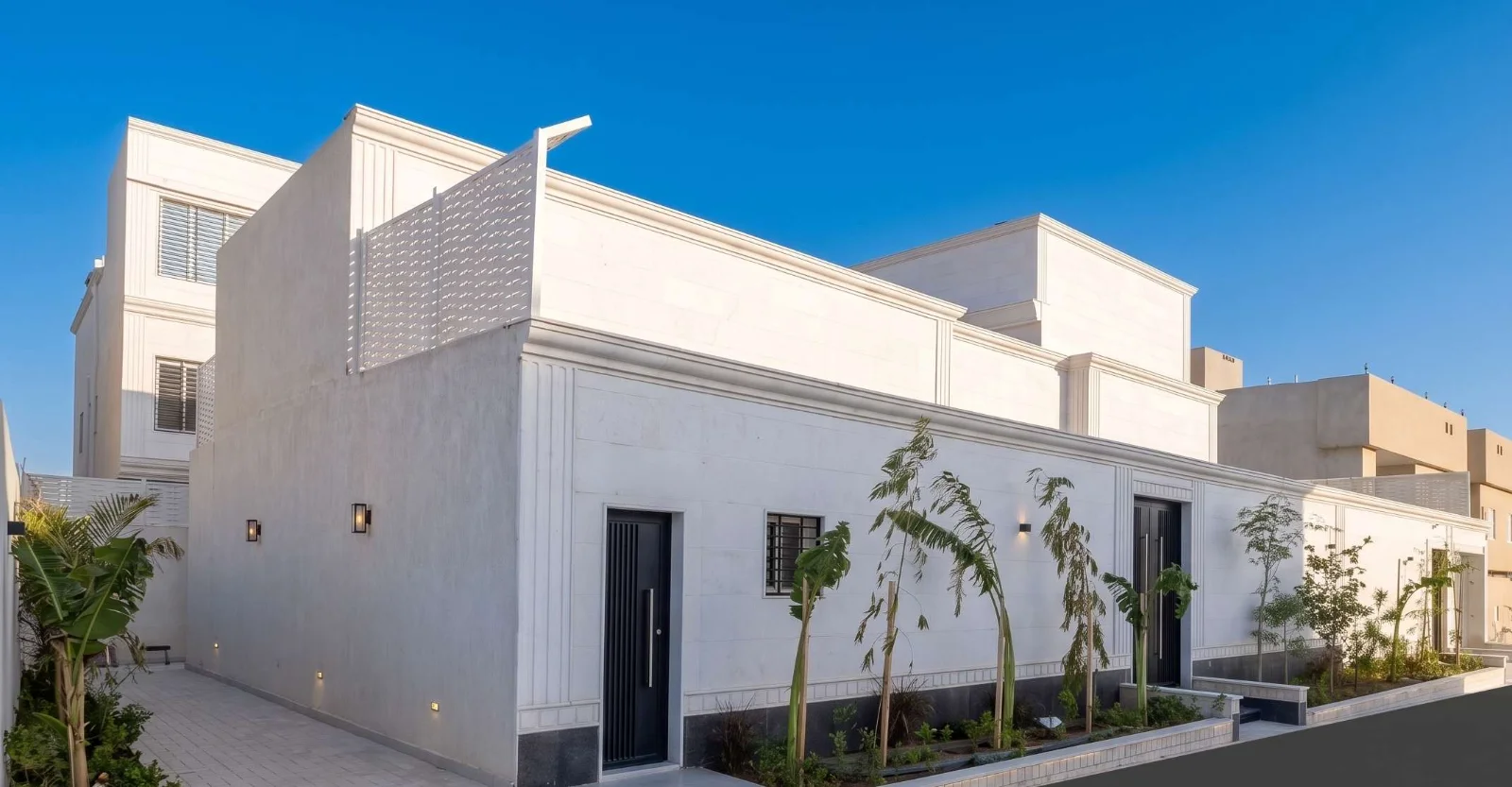 منظور تصميمي نهاري لواجهة الفيلا الزاوية بتكسية حجرية وطابع نيوكلاسيكي، مع مشربية مفرغة أعلاها وزراعة حديثة على امتداد سور الحد.